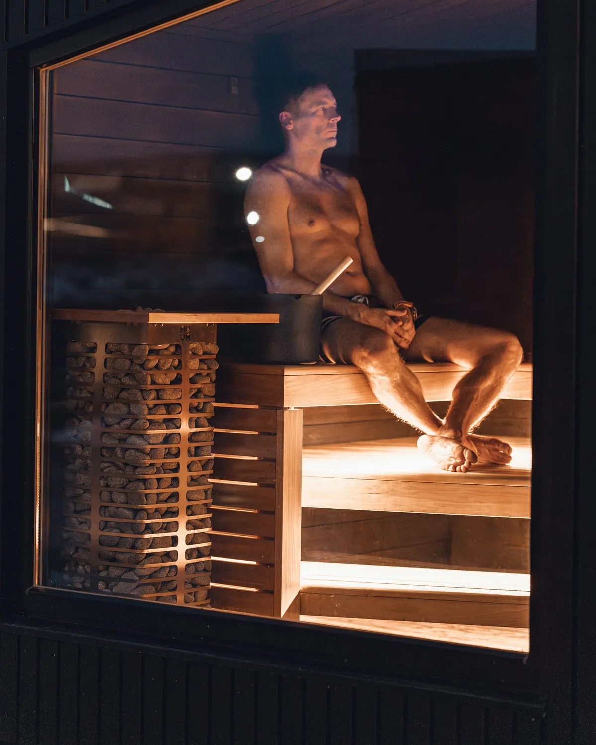 Man relaxing in a softly lit sauna at night
